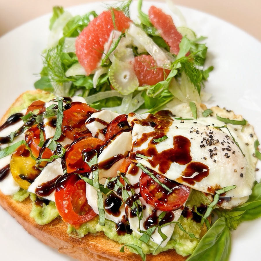 Avocado toast with fresh mozzarella, tomatoes, basil, balsamic and a fried egg, with grapefruit-fennel salad